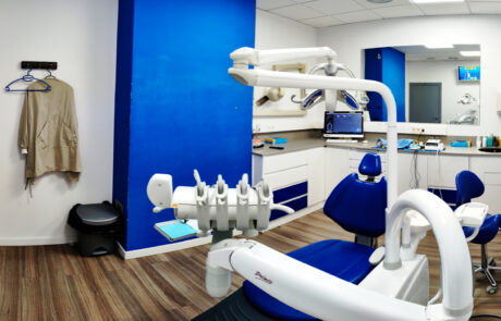 Box 4 Fotografia d'un box on al primer pla es veu una cadira odontològica, una paret blava i mobles blans amb algun detall del mateix color que la paret i la cadira.