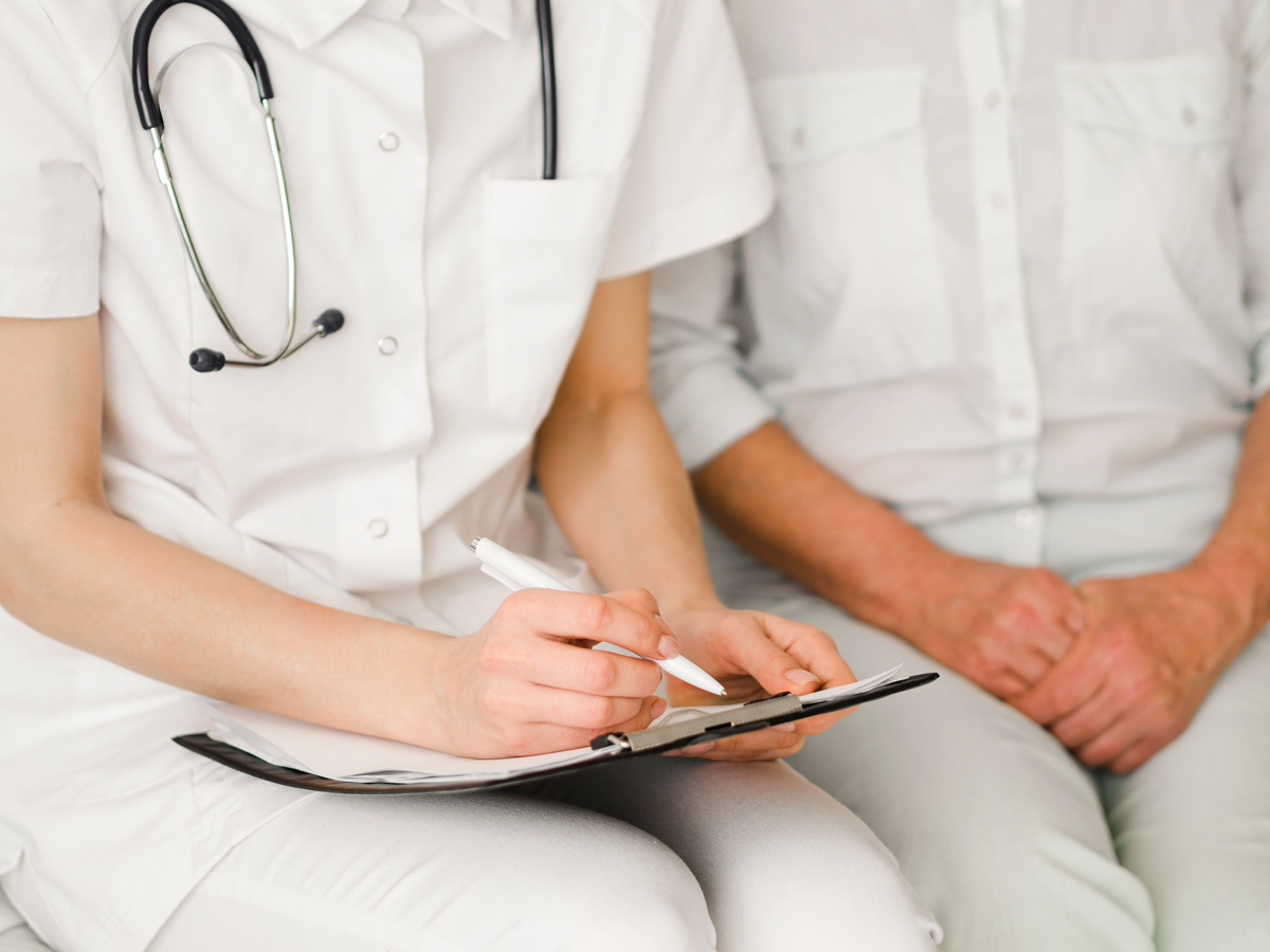 Primer pla d'un metge amb una carpeta escrivint.