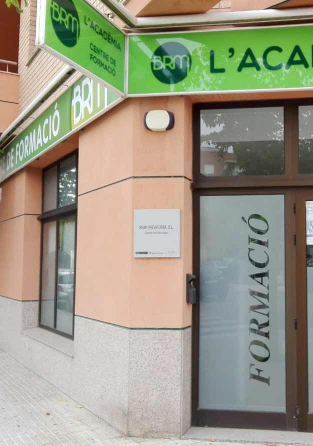 Façana on hi ha un cartell verd amb tipografia negra i una porta retolada que posa formació.