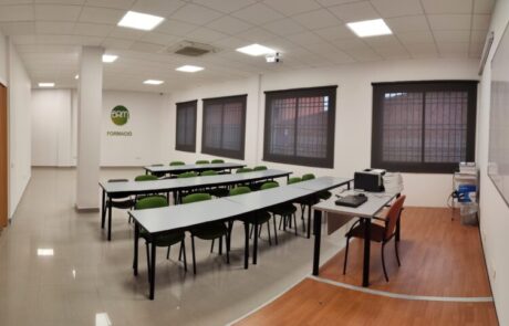 Aula amb taules i cadires i llibres al damunt.