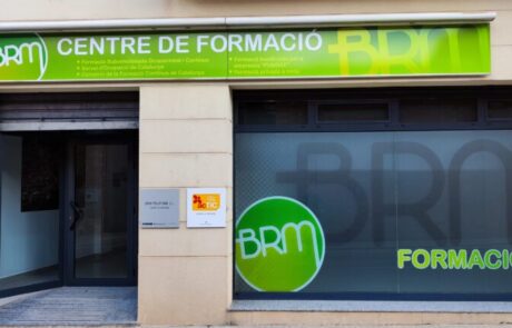 Façana on hi ha un cartell verd amb tipografia negra i una porta retolada que posa formació.